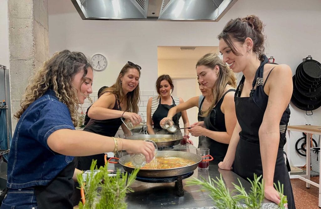 Grupo participando en un taller de paella valenciana en una cocina-escuela de Valencia