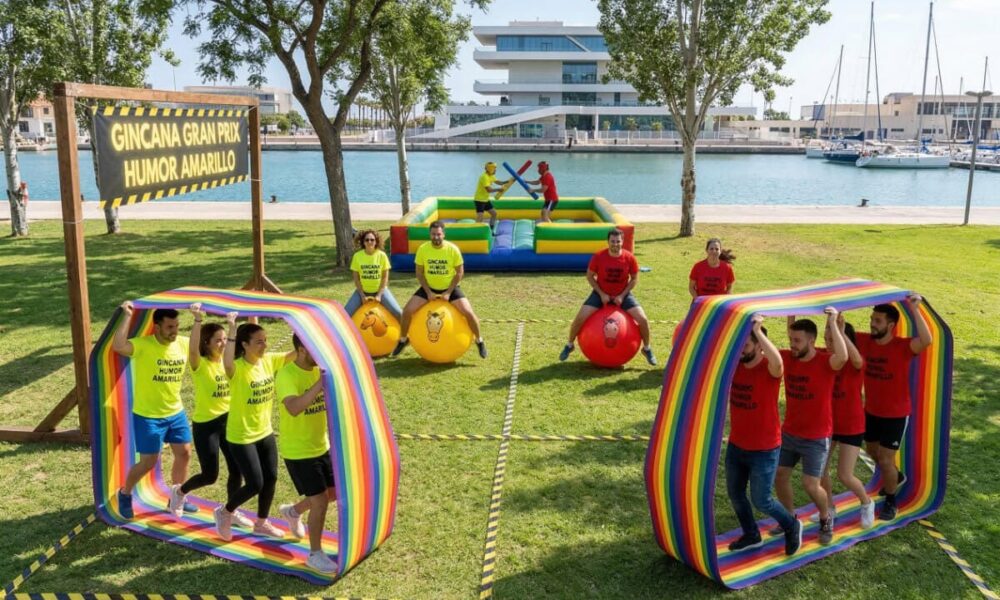 Dos equipos compitiendo en la gincana Gran Prix Humor Amarillo en Valencia con pruebas hinchables junto a la Marina